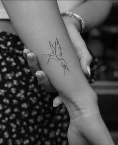 a woman's arm with a small bird tattoo on the left side of her arm