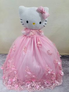 a stuffed hello kitty doll in a pink dress with flowers on it's skirt