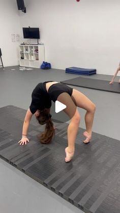 a woman in black shirt doing a handstand on a mat