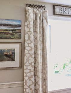 the curtains are hanging on the wall by the window in the room with pictures and paintings