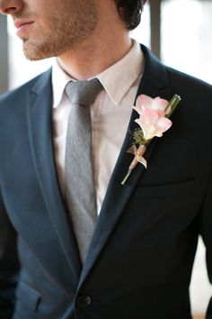 a man wearing a suit and tie with a flower in his lapel pin on his lapel