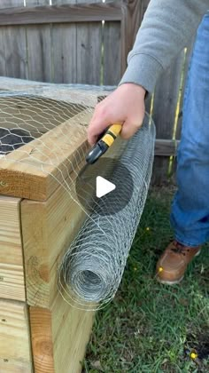 a person is using a tool to attach a chicken wire on top of a wooden box