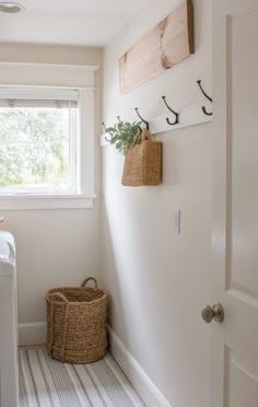 a laundry room with white walls and striped flooring, two baskets on the wall