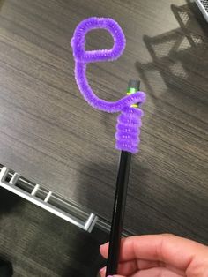 a person holding a purple pen with the number nine on it's end and an object in the background