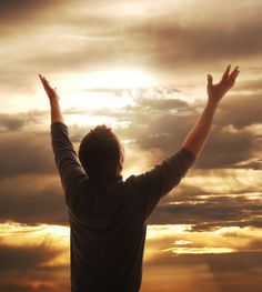 a man standing in front of a painting with his hands raised up to the sky