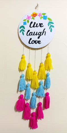 a sign that says live laugh love with tassels hanging from it