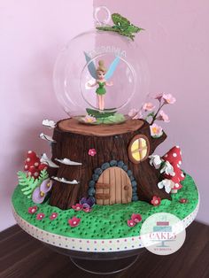 there is a cake that looks like a tree stump with a tinkerbell on top