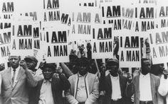 a group of black men holding up signs in front of a wooden wall that says i am man