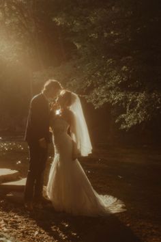 a bride and groom are standing in the sunbeams at their outdoor wedding ceremony