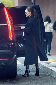 the woman is getting out of her car and stepping into the vehicle with her handbag