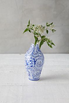 a blue and white vase with flowers in it sitting on a table next to a wall