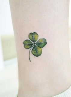 a small four leaf clover tattoo on the ankle, with green leaves in the shape of a shamrock