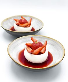 two white plates with strawberries and sauce on them