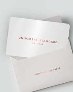 two white and gold business cards on top of each other with the words universal standard