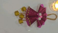 a pink and gold hair clip next to a candle on a white surface with glitter