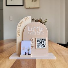 a wooden table with a sign and pictures on it that says welcome to little wild one