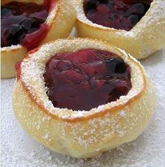 four pastries covered in powdered sugar and jelly