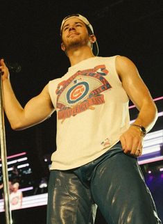 a man standing on top of a stage holding a microphone in his right hand and wearing headphones