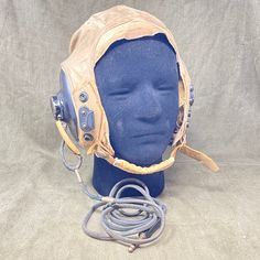 Khaki cotton twill flying helmet with black rubber earpieces. Fitted into the rubbers are earphones with fabric-covered leads connecting to a red plastic jack. The inner forehead section and headphone cups are lined with chamois leather. The helmet has three leather loops on the rear to retain goggles. Two of these loops are secured with press studs. There is a buckle and snap-fastening chin strap with velour padding. Brass press stud fittings for an oxygen mask are also present. Acne Denim, Oxygen Mask, Sculpted Doll, Denim Projects, Design Skills, Sirens, Funky Art, Press Studs, Black Rubber