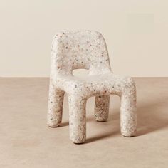 a white plastic chair sitting on top of a cement floor covered in confetti