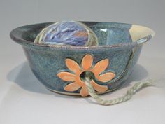 a blue bowl with orange flowers and yarn in it