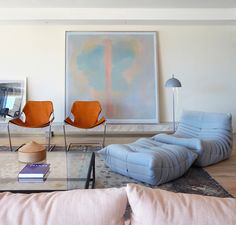 a living room with couches, chairs and a painting on the wall behind it