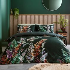 a bedroom with green walls and a bed covered in a black comforter set that has colorful leaves on it