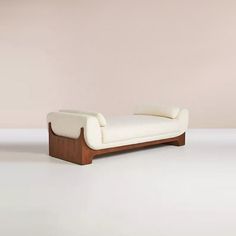 a white couch sitting on top of a wooden floor next to a pink wall in an empty room