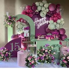 a table topped with lots of pink and white flowers next to a sign that says happy birthday