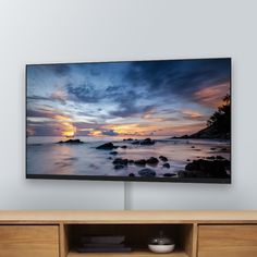 a flat screen tv sitting on top of a wooden entertainment center next to a wall