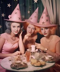 three women wearing pink hats sitting at a table