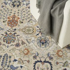 an area rug with various colors and patterns on the floor next to a white couch