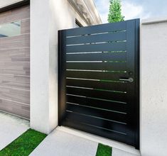 an entrance to a modern home with grass in the foreground and a black gate