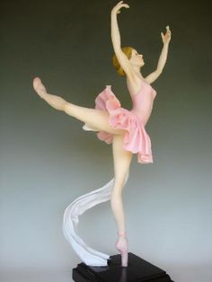 a figurine of a ballerina is posed on a black base and holds her arms in the air