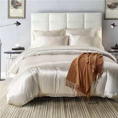 a bed with white sheets and pillows in a bedroom next to two pictures on the wall