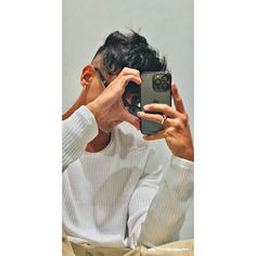 a man taking a photo with his cell phone while sitting in front of a mirror