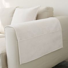 a white couch with two pillows on it's back and one arm folded down