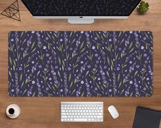 a desk with a keyboard, mouse and purple flowers on the table next to it