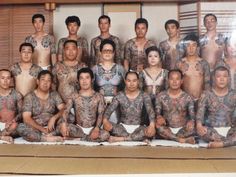 a group of men and women with tattoos on their body sitting next to each other