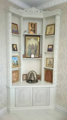 a white bookcase with pictures on it in a room filled with wallpapers