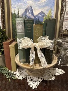 three books are wrapped in white ribbon on a table with other books and decorations behind them