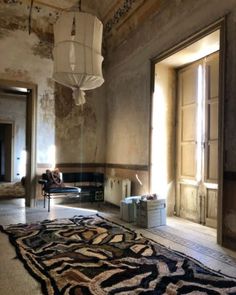 a living room with a rug on the floor next to a chair and lamp fixture