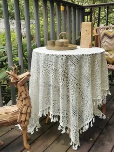 a table with a white doily on it sitting on a porch next to a rocking chair