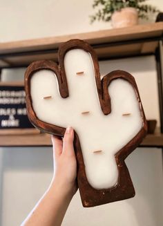 a person holding up a piece of bread shaped like a cactus