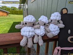 three little stuffed sheep hanging from the side of a fence next to a wooden door