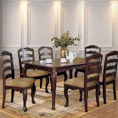 a dining room table with six chairs and a vase on the rug in front of it