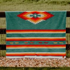 a colorful blanket is hanging on a fence