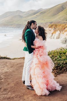 a man and woman standing next to each other near the ocean