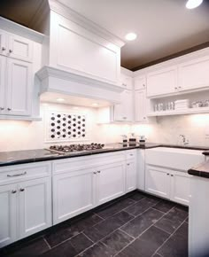 a kitchen with white cabinets and black counter tops