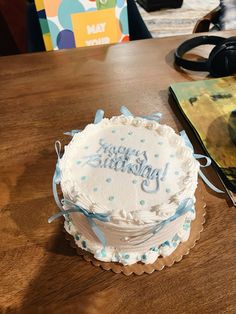 a birthday cake sitting on top of a wooden table next to a pair of headphones